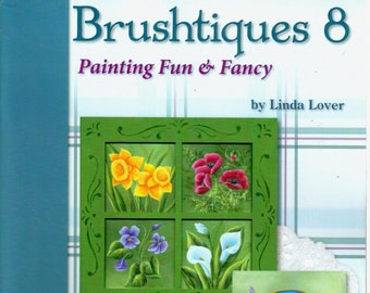 May include: A book titled "Brushtiques 8: Painting Fun & Fancy" by Linda Lover. The cover features a green window frame with four painted scenes: daffodils, red poppies, purple violets, and white calla lilies. Below the window frame are two round paintings, one of a red barn and the other of a snowy house. The book is published by Viking Woodcrafts.