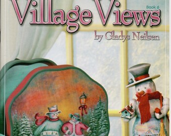 May include: A set of three painted wooden ornaments featuring winter scenes with snowmen. The ornaments are shaped like a round box, a plate, and a small snowman. The ornaments are painted in shades of blue, green, white, and red. The text "Village Views Book 6 by Gladys Neilsen" is printed on the top of the image.