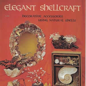 Puede incluir: Una portada de libro con el título "Elegant Shellcraft" y el subtítulo "Accesorios decorativos usando conchas naturales". La portada presenta una variedad de artesanías de conchas, incluyendo un espejo, una concha de nautilus, un pájaro y un hongo.
