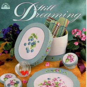 Puede incluir: Un libro titulado "Still Dreaming" de Avis Braun, CDA, que presenta diseños pintados de flores y bayas en platos, cajas y otros artículos decorativos.