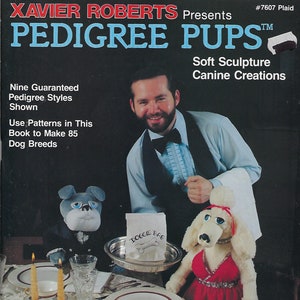 Könnte beinhalten: Ein Mann in einem weißen Hemd und einer schwarzen Weste hält eine weiße Pudelpuppe, die ein rotes Kleid trägt. Eine graue und weiße Bulldoggenpuppe hält eine weiße Tasche mit der Aufschrift "Doggie Bag". Die Puppen sitzen an einem Tisch mit einer weißen Tischdecke und Kerzen. Der Text auf dem Bild lautet "Xavier Roberts Presents Pedigree Pups TM Soft Sculpture Canine Creations Nine Guaranteed Pedigree Styles Shown Use Patterns in This Book to Make 85 Dog Breeds Short Body Type Measures 24" high Tall Body Type Measures 27" high #7607 Plaid".