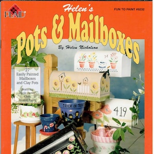 May include: A book cover with a red background and the title "Helen's Pots & Mailboxes" in yellow letters. The cover features a variety of painted mailboxes and flower pots, including a mailbox with a "Trick or Treat" design and a number "419" on the side.
