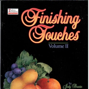 Puede incluir: Portada de libro con el título "Finishing Touches Volume II" en escritura naranja y roja sobre fondo negro. La portada presenta una naturaleza muerta de varias frutas, incluyendo uvas, peras, melocotones y ciruelas.