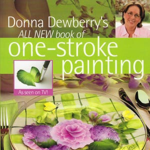 Può includere: Copertina del libro "Donna Dewberry's ALL NEW book of one-stroke painting" con un piatto dipinto. Il piatto presenta una rosa rosa, fiori viola e foglie verdi. Il testo "As seen on TV!" è visibile.