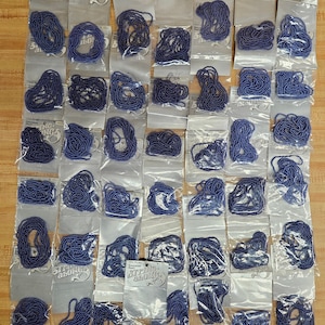 Könnte beinhalten: Eine Sammlung von 36 Packungen blauer Perlen, jede mit der Aufschrift "String-Along's".
