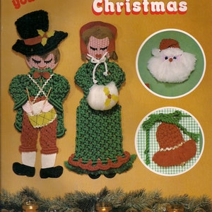 Può includere: Un libro di artigianato vintage intitolato "Knotty Little Christmas" con istruzioni per 8 progetti. La copertina presenta illustrazioni di un uomo e una donna in abiti di maglia verde e rosso, una testa di Babbo Natale bianca e una campana marrone su uno sfondo a scacchi verde e bianco.