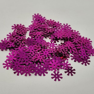 Puede incluir: Un montón grande de lentejuelas magenta en forma de estrella. Las lentejuelas son brillantes y tienen un acabado metálico.