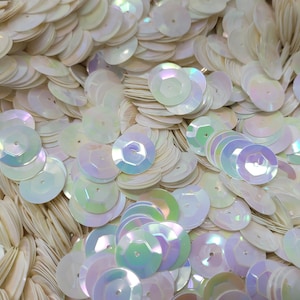 May include: A close-up of iridescent white sequins, perfect for crafting or embellishing clothing and accessories.