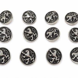 May include: A set of twelve circular silver-toned metal buttons, each featuring a raised relief design of a rampant lion on a textured background. The buttons are arranged in three rows of four, displaying a consistent metallic finish and detail.