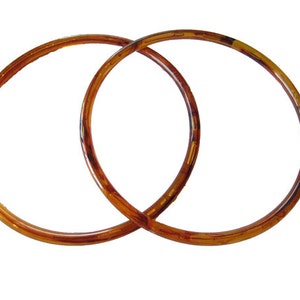May include: Two brown plastic rings, likely for a handbag or purse.