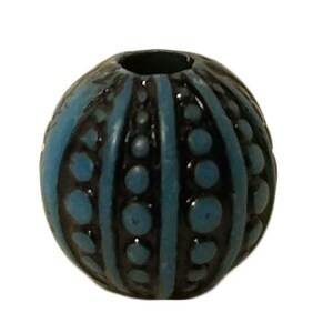 May include: A blue and black round bead with a textured surface. The bead has a raised pattern of stripes and dots.
