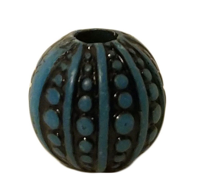 May include: A blue and black round bead with a textured surface. The bead has a raised pattern of stripes and dots.