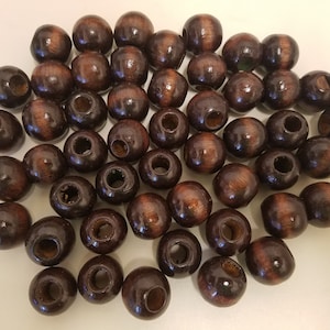 May include: A large group of dark brown wooden beads with a hole through the centre of each bead. The beads are arranged in a random pattern.