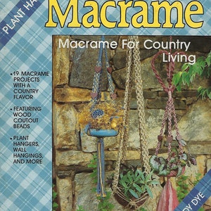 May include: A book cover with the title "PLAID'S Macrame Macrame For Country Living" by Sandy Dye. The cover features three macrame plant hangers with different colours and designs hanging against a stone wall.