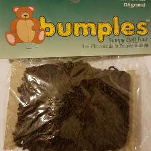 May include: A package of brown doll hair labeled "bumples" Bumpy Doll Hair Les Cheveux de la Poupée Bumpy. The package says Net. Wt. 1 oz. (28 grams).