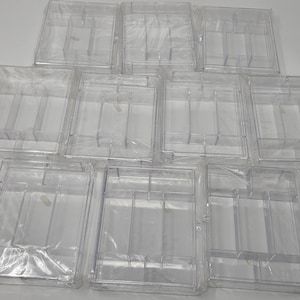 以下が含まれることがあります： 10個の透明なプラスチック製収納容器のコレクション。各容器は長方形で、小さなアイテムを整理するための複数の内部仕切りがあります。容器は個別に透明なプラスチックで包装されています。
