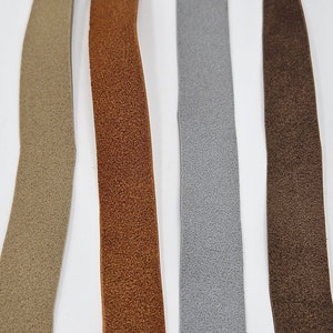 May include: Four strips of suede fabric in different colors: beige, brown, gray, and dark brown.