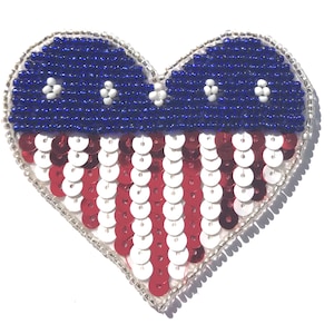 May include: A heart-shaped beaded patch with a red, white, and blue American flag design. The top of the heart is made of blue beads with white stars, and the bottom is made of red and white sequins.