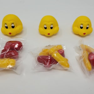 May include: Three yellow rubber toy heads with black eyes and red lips, each in a separate plastic bag with red and yellow rubber toy food items.