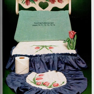 May include: A bathroom set with a tulip theme. The set includes a shelf, a towel, a toilet seat cover, and a rug, all decorated with red tulip designs. The text "TULIP BATHROOM SET" is visible. The set has a blue and white color scheme.