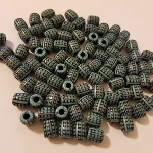 Puede incluir: Un mont&oacute;n grande de cuentas de pl&aacute;stico de color turquesa y negro con un patr&oacute;n. Las cuentas son cil&iacute;ndricas y tienen un peque&ntilde;o agujero en el centro.