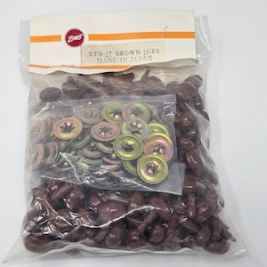 May include: A clear plastic bag containing brown plastic fasteners and gold-colored metal washers. The bag has a label that reads "ETN-17 BROWN 1GRS MADE IN JAPAN". The fasteners are a dark brown color.