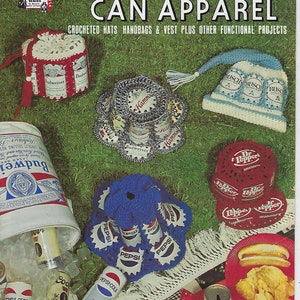May include: A book cover with the title "Aluminum Can Apparel" and a picture of crocheted hats, handbags, and vests made from aluminum cans. The book cover is green and features a red, white, and blue American flag.