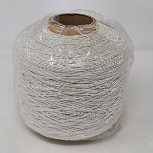 May include: A spool of white elastic cord wrapped in clear plastic. The cord is wound tightly around a cardboard core.