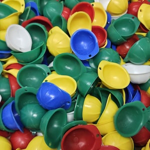 May include: A pile of colorful hard hats in various colors, including green, yellow, red, blue, and white. The hats are made of plastic and are likely for construction or safety purposes.