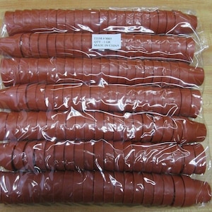 Peut inclure: Un sac en plastique transparent rempli de 100 bouchons de bouteille en caoutchouc rouge. Le sac porte une étiquette indiquant "ITEM # 9005 QTY: 1 GR MADE IN CHINA".