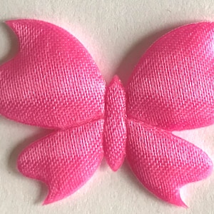 Può includere: Un fiocco di raso rosa con effetto 3D. Il fiocco ha la forma di una farfalla.