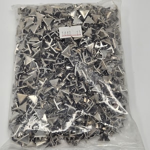 May include: A clear plastic bag filled with numerous silver-colored, triangular metal studs. The studs are densely packed, reflecting light. A label with the numbers "1440 11" is visible. The bag is labeled "MADE IN TAIWAN R.O.C."