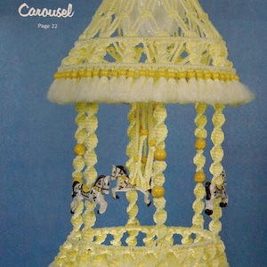 May include: A yellow macrame carousel mobile with a white fringe and wooden beads. The mobile features three porcelain horses with black and white markings. The text "Kiddie Carousel Page 22" is visible in the top left corner of the image.