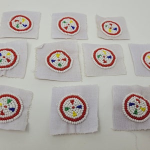 May include: Ten white fabric squares with red, white, blue, yellow, and green beaded circles in the center.