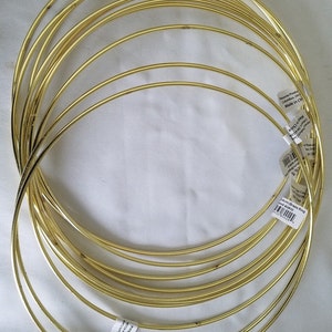 May include: A set of ten gold-colored metal hoops, perfect for crafting projects. The hoops are all the same size and are stacked on top of each other.
