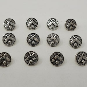 Puede incluir: Doce botones de metal plateados con un diseño de bolos y bola. Cada botón tiene un diseño en relieve de dos bolos cruzados y una bola de bolos.