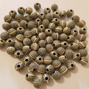 May include: A large group of off-white round beads with a black and white striped pattern. The beads are about 1 inch in diameter.