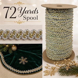 Könnte beinhalten: Eine 72 Yards Spule mit dekorativem Band in wellenförmiger, gold- und silberfarbener Metallic-Optik. Das Band ist in einer Detailaufnahme zu sehen und am Rand eines dunkelgrünen Samtstoffs mit goldenem Schneeflocken-Stickmuster angebracht.