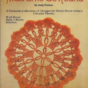 May include: A book cover with a macrame design in orange and brown. The title is "Macrame Go Round" by Judy Palmer. The book is about creating macrame designs for home decor using a circular theme. The book cover also includes the text "Wall Decor, Baby's Room, Kitchen" and "#7430, Plaid".