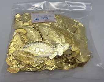 May include: A clear plastic bag containing 100 gold-colored metal fish-shaped charms. Each flat charm features a textured scale pattern and a small loop at the top. A white label on the bag displays the text 100 PCS and MADE IN TAIWAN R.O.C.
