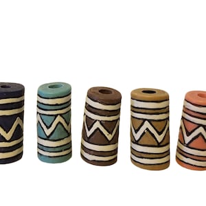 May include: Five decorative wooden cylinders with a geometric pattern. The cylinders are painted in various colors, including blue, teal, brown, beige, and pink.