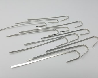 May include: A collection of silver-colored metal bookmarks, each featuring a long, flat, straight stem and a curved hook at one end. These slender, polished metal accessories are designed to hold pages in place within a book or journal.