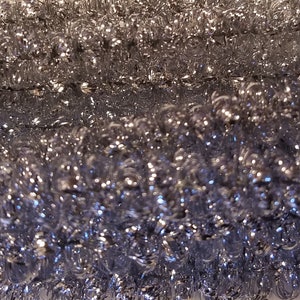 May include: Close-up of silver tinsel garland, a decorative item for Christmas or other celebrations. The tinsel is tightly wound and creates a shimmering effect.
