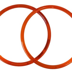 May include: Two orange plastic hoops, each with a slightly different diameter, are stacked on top of each other.