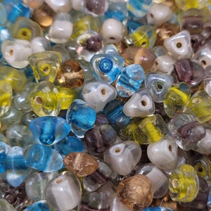 May include: A collection of colorful glass beads in various shapes and sizes. The beads are mostly triangular and have a translucent appearance. The colors include blue, green, yellow, brown, and white.