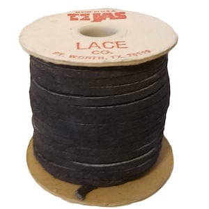Könnte beinhalten: Eine Spule mit schwarzem Lederband, beschriftet mit "Texas Lace Co. Ft. Worth, TX 76119" und "Made in USA".