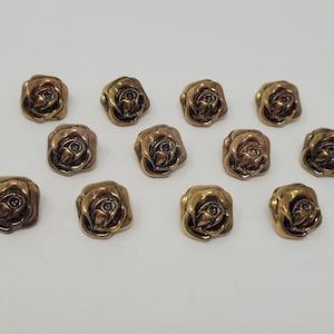 May include: Twelve gold-toned metal buttons with a rose design. Each button features a raised, detailed rose with a centre accent.