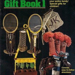 Op de afbeelding: Een vintage macramé cadeau boekcover met tennisracket covers, een plantenhouder en golfclub covers. De covertekst luidt "Macramé Gift Book 1" en "Cadeaus van $3 tot $20 voor uw hele gezin! Speciale cadeaus voor kinderen!"