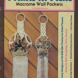以下が含まれることがあります： ロゼラ・アイラーマン著「ポジーのためのポケット：マクラメ壁ポケット」というタイトルの本。表紙には、ドライフラワーを飾ったマクラメの壁ポケットが2つ描かれている。この本には、15のデザイン、ステップバイステップの指示、フルカラーの写真が含まれている。