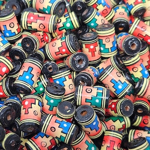 Peut inclure: Un tas de perles en bois colorées avec des motifs géométriques. Les perles sont noires, rouges, jaunes, vertes et bleues. Elles sont toutes de forme cylindrique et ont un trou au centre.